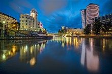 Une voie d'eau assez large, avec d'un coté un batiment un peu ancien eet de l'autre un peu moderne, tous deux avec une tour et un immeuble.