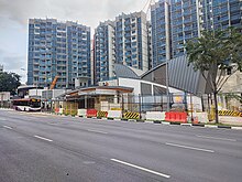 Entrance of the station with curved zinc roofs, with buildings under construction in the background