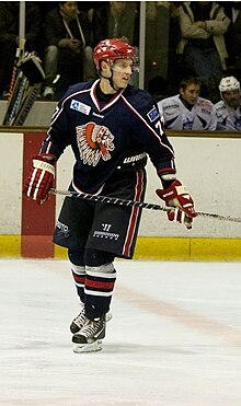 Photographie d'un joueur en tenue de hockey, patins aux pieds.