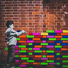 A mural by Hendog of a boy placing coloured bricks on top of each other, creating a wall.