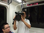 台湾のEETVの報道番組のカメラマンによる列車内での撮影。カメラを肩にかつぎ、立位（立った姿勢）での撮影。