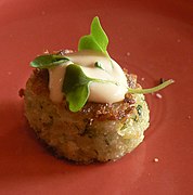 Un crabcake adornado con salsa y microverde.