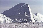 A massive iceberg in the sea full of smaller icebergs.