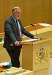 Johan Pehrson vid talarstolen som är prydd med Stora Riksvapnet i Sveriges riksdag