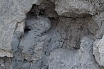 A crack in one of the walls of Abu Loza's Bath reveals a portion of its internal structure, showcasing the materials used in its construction. This includes plaster, stones, and palm trunks