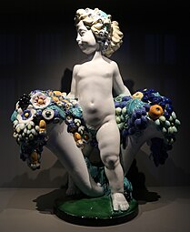 Secessionist putto with two cornucopias with floral cascades, very similar to the ones found in a lot of Art Deco of the 1910s and 1920s, by Michael Powolny, designed in c. 1907, produced in 1912, ceramic, Kunstgewerbemuseum Berlin[233]