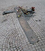 Une croix stylisée au sol, entourée par les pavés du sol, avec des roses.