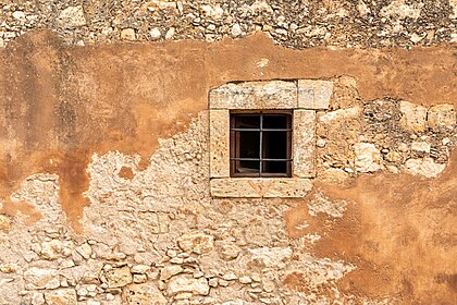 Janela do mosteiro de Arcádi, um mosteiro histórico na área da comunidade de Amnatou, no município de Retimno, na unidade regional de Retimno, em Creta. Acredita-se que a primeira forma do mosteiro tenha sido construída no período de 961 a 1014, ou nos primeiros anos da ocupação veneziana. A atual igreja data do século XVI e é caracterizada pela influência do Renascimento. Essa influência é visível na arquitetura, que mistura elementos românicos e barrocos. Já no século XVI, o mosteiro era um local de ciência e arte e tinha uma escola e uma rica biblioteca. Em um platô, o mosteiro é bem fortificado e cercado por um muro espesso e alto. (definição 6 720 × 4 480)