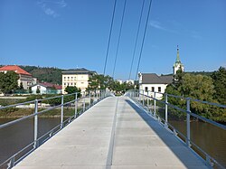 Budovy škol a kostel sv. Petra a Pavla z lávky přes Berounku