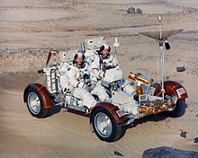 Charles Duke et John Young manœuvrant une version d'entraînement du rover lunaire Apollo. Ils sont revêtus d'une combinaison spatiale A7L.