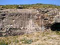 Photo en couleur montrant un mur avec une trace blanche éclatée au milieu, signe de l'explosion d'un projectile (obus)