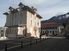 Photo d'une place où se situe un bâtiment orné d'un drapeau français, avec un autre bâtiment en fond.