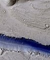 Porção de uma trincheira (Fossae) em Elysium Planitia, visto pela HiRISE sob o programa HiWish. O azul indica provavelmente congelamento sazonal.