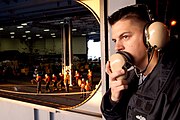 YN2 Patrick Shuman mans his station as deck control phone talker during a replenishment at sea (RAS) between Military Sealift Command (MSC) USNS Bridge (T-AOE-10) and USS Nimitz (CVN-68).