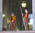 Il portone di bronzo, entrata principale del Palazzo Apostolico, sorvegliata da due alabardieri della Guardia svizzera pontificia. Dietro si scorge la scala.