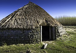 L'habitat rural breton au Haut Moyen Âge se distingue peu de l'habitat de l'âge du fer, surtout dans les zones de faible romanisation. Malgré l'utilisation de pierres sèches et la permanence de quelques villae romaines, les maisons rondes et les forteresses à talus refont massivement leur apparition (sites de Gwithian ou Pant-y-Saer) avec en parallèle l'abandon rapide des cités. Quant aux ressources numismatiques, la répartition des pièces de monnaie romaines retrouvées en Grande-Bretagne correspond sans surprise aux zones les plus fortement romanisées. (Image de gauche : schéma à étapes du bâti d'une roundhouse à Bradbury. Image au centre : reconstitution d'une roundhouse sur le site archéologique de Brigantium. Image de droite : carte des découvertes de numéraire sur toute la période romaine en Grande-Bretagne.)