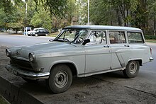 Voiture allongée, de couleur grise, avec un capot aux formes arrondies typique des années 1960.