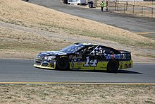 A view of the left-hand side of a black and yellow race car with the number 14