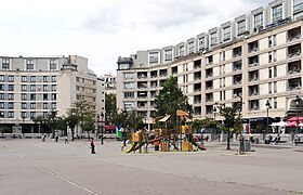 Place Henri-Frenay, où Jean Rochefort est assis sur un des bancs en pierre.