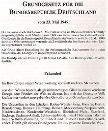 Première page du texte de la loi fondamentale de la république fédérale d'Allemagne, en allemand. En haut de la page, centré et en gras, l'intitulé : Loi fondamentale de la république fédérale allemande du 23 mai 1949. Après 9 lignes de texte dactylographié, centrées et dans un police non accentuée, le titre Préambule, centré et en gras, se trouve au milieu de l'image ; suivent les premiers paragraphes du texte du préambule, dans une police non accentuée.