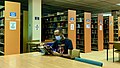 Student wearing mask and reading in library.