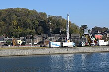 photo couleur de quelques attractions en bord de Meuse avec des maisons, un vide-bouteilles et la colline en arrière-plan