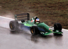 Photo d'une monoplace verte roulant sur une piste trempée