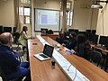 Four people sitting at a table looking at a projector screen