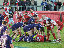 Des joueurs de rugby forment un ruck autour du ballon au sol.