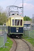 Photo couleur d'un tramway électrique de face sur rails, le toit est gris, la voiture est beige en haut et bleu en bas.