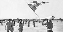 An officer at an airfield salutes the Swedish flag