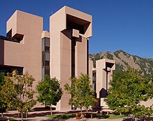 The Mesa Laboratory of the National Center for Atmospheric Research, a series of brown boxlike buildings, stands in front of a mountain.