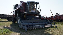 Vooraanzicht van een rode maaidorser met een zwarte opraper als voorzetstuk.