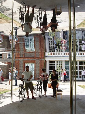 Cada verano, la Serpentine Gallery tiene un pabellón de arquitectos eminentes que no han diseñado nada anteriormente en el Reino Unido. El de este año, de Kazuyo Sejima y Ryue Nishizawa, tiene un techo de láminas de aluminio pulido sobre esbeltas columnas. Mirando desde adentro, uno ve la vista exterior y su reflejo en el techo. La realidad y el reflejo se fusionan sin problemas. Aquí el reflejo de la galería aparece como un segundo piso, pero subiendo más llegamos a los reflejos de los ciclistas, al revés.