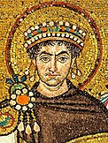 A close up photograph of a mosaic of a person painted on a golden colored background. The person has a dark brown cloth covering up his upper body till the neck, three jewels on his right shoulder, a crown with two pendants each hanging from both ends and an aura like circle around his head