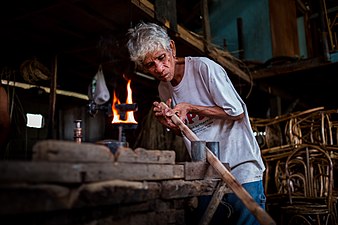 Craftsman in the Philippines heat bending rattan for furniture-making