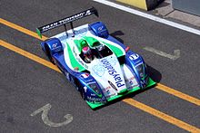 Photo en plongée d'une voiture de course bleue, blanche et verte.