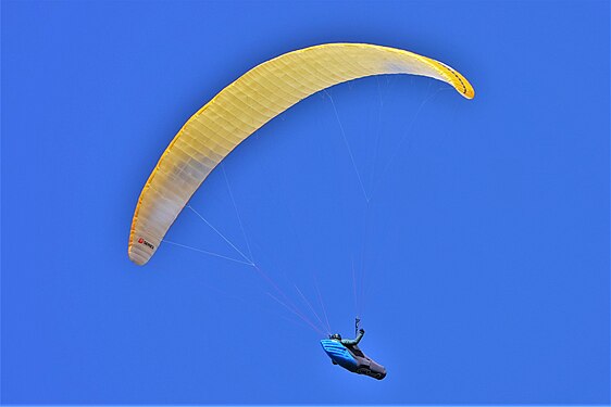 Paraglider under a yellow parachute on an azure background in Vanoise