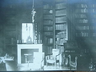 Bibliothèque avec rayonnages et livres reliés. Cheminée blanche.