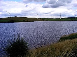 Lake with wind turbines beyond it