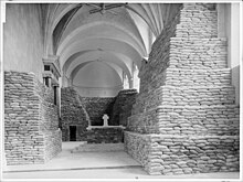 Photographie en noir et blanc du chœur de l'église des Cordeliers, donc les murs et l'autel sont recouverts jusqu'à mi-hauteur d'un empilement pyramidal de sacs de sable.