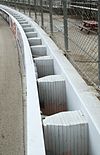 A white-colored SAFER barrier retrofitted in front of a concrete wall