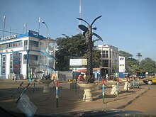 A road intersection with some two-story buildings and bollards on the curb.