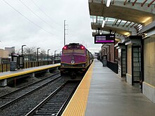 A passenger train leaving a station with two tracks and two platforms