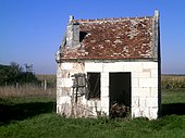 Photographie en couleurs d'une petite maisonnette d'une seule pièce, abandonnée.