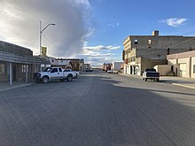 Standing in the middle of the main street in the business district of Harlowton, with buildings on either side.