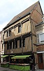 Maison du XVe siècle entièrement en pans de bois, façade à encorbellements et son étal de fruits et légumes.