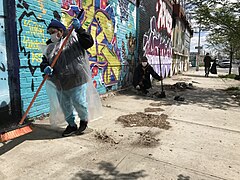 Street sweepers clearing a New York sidewalk of dust and dirt using brooms