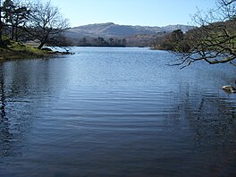 A lake surrounded by trees with mountains beyond