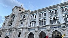 An arched neoclassical building with hanging PTT banners